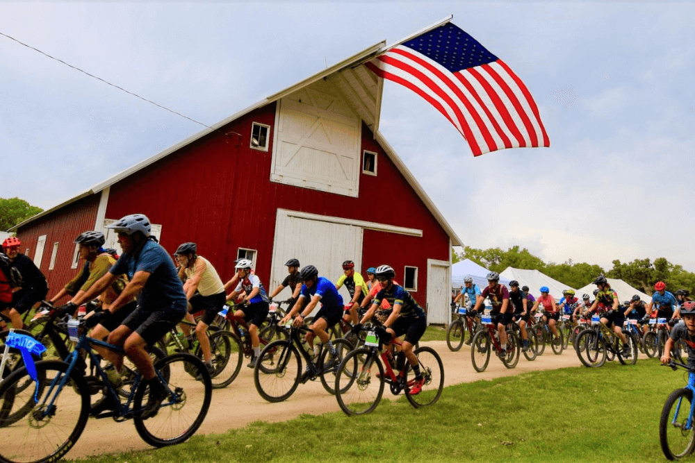bike race past red barn with american flag